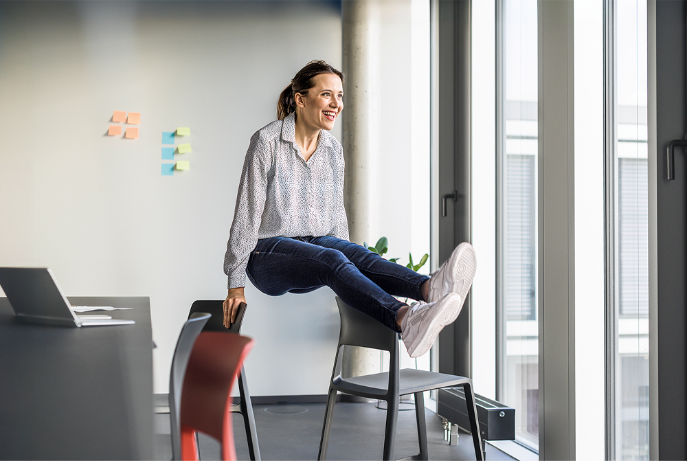 Frau, die sich zwischen zwei Stühlen hochdrückt